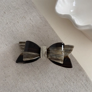 Macro detail of marble pattern acetate hair clip with gold France Handmade text engraving
