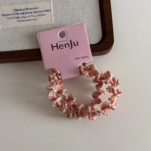 Close-up of pink and white spiral braided hair tie on display card with cozy wooden decor
