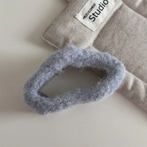 Gros plan sur un chouchou en peluche grise avec de fins reflets argentés et texture douce