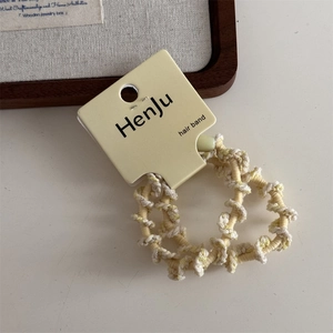Detailed macro view of yellow braided elastic hair band with a brand display card
