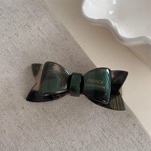 Detail of green tortoiseshell acetate bow hair clip with gold France Handmade logo