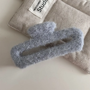 Détail de la pince à cheveux en feutre gris avec une texture pelucheuse douce