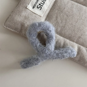 Gros plan sur la pince à cheveux en peluche grise avec fils argentés et texture douce