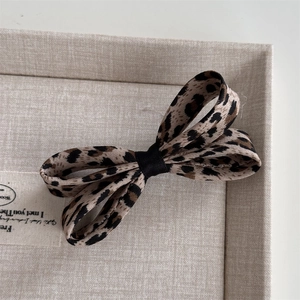 Dettaglio molletta per capelli con fiocco leopardato e nastro nero in confezione