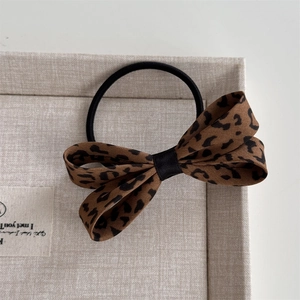 Dettaglio dell'elastico per capelli con fiocco leopardato su espositore in lino