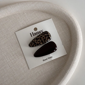 Details von Haarklammern mit Leopardenmuster und Dunkelbraun auf einer Displaykarte