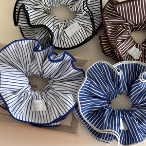 Close-up of striped scrunchies in blue and black colors with delicate logo tags