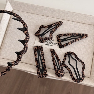 Leopard print hair accessory set with headband and clips on a beige tray