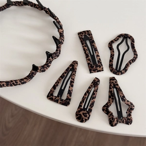 Detailed close-up of leopard print fabric BB hair clips and headband set in various shapes