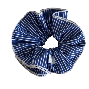 Blue and white striped scrunchie made of pleated fabric with delicate edge stitching