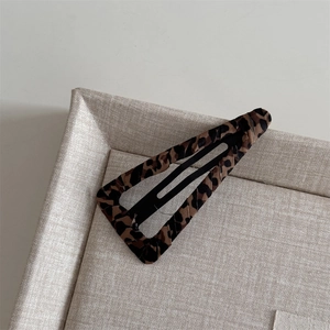 Close-up of leopard print fabric wrapped BB hair clip showing pattern and material texture