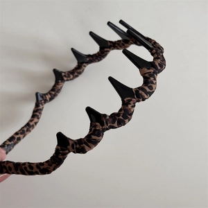 Detail of leopard print fabric headband featuring a black plastic wide-toothed inner grip