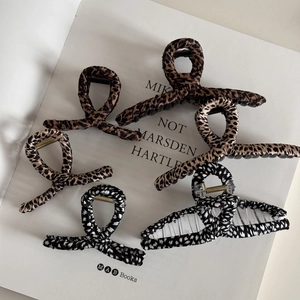 Detail view of five assorted leopard and heart pattern fabric wrapped claw clips on a book