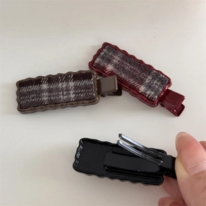 Detailed view of plaid fabric hair clips with wavy edges and metal duckbill buckle