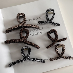 Set of 6 leopard print fabric wrapped hair claws in various patterns on a white book