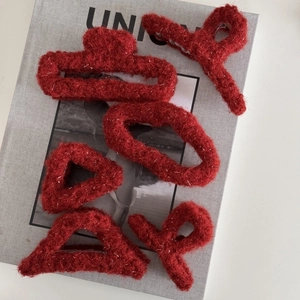 Detailansicht roter Plüsch-Haarklammern mit glitzernden Silberfäden und Stricktextur