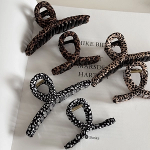 Detailed view of leopard print hair claws in various sizes on a white book backdrop