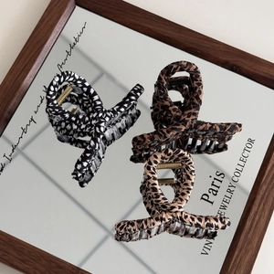 Detailed view of leopard print and plaid fabric hair claws on a vintage mirror surface