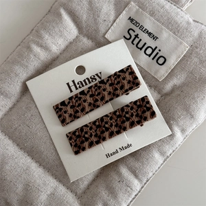 Detailed macro view of two rectangular leopard print hair clips on a white brand card