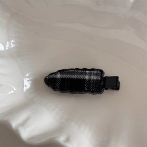 Detail of checkered fabric hair clip with a scalloped edge on a white background