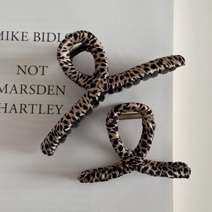 Detail view of large and small leopard print fabric hair claws on a book
