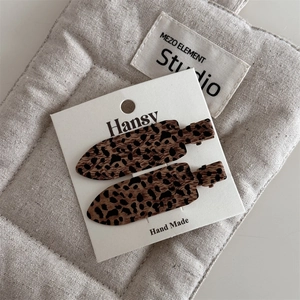Close-up of vintage leopard print hair clips on a textured card for handmade styling
