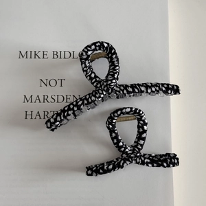 Close-up of black and white patterned fabric wrapped hair claws on a book background