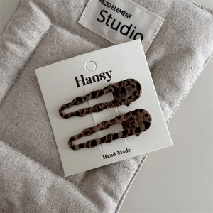 Set of two vintage leopard print duckbill hair clips displayed on a soft fabric pouch