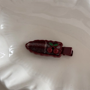 Macro shot of dark red plaid hair clip with cute cherry ornaments on white tray