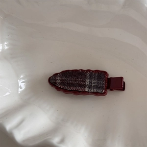 Detail of a vintage wine red hair clip with checkered fabric and wavy edge design