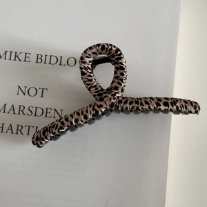 Close-up of leopard print fabric wrapped hair claw clip with black plastic teeth detail