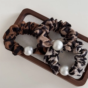 Vintage leopard print scrunchies with elegant pearls on a wooden tray accessory set