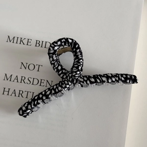 Detail view of large leopard fabric hair claw clip with golden metal spring and floral texture