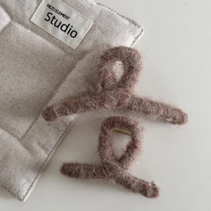 Primer plano de dos pinzas para el pelo de peluche marrón con piel sintética y muelle dorado