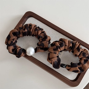 Detail of leopard print scrunchies with white pearl and black bead on a display tray