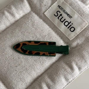 Detail view of the green leopard print fabric texture on a geometric metal hair clip