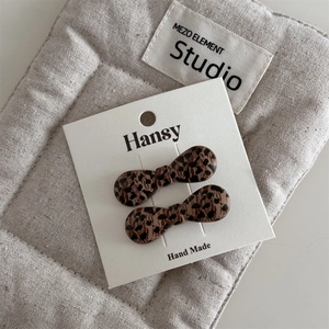Detail view of handmade leopard print bow hair clips set on a white display card