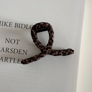 Detailed view of large leopard print fabric wrapped claw clip on a stylish white card