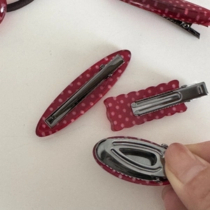 Detail view of red polka dot hair clips with sturdy metal duckbill clip mechanisms