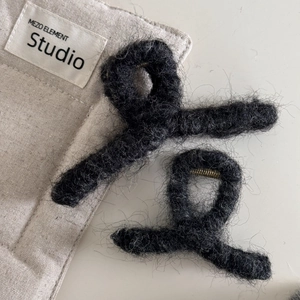 Detalle de dos pinzas de pelo de felpa gris oscuro con textura suave de invierno y muelle