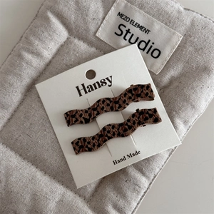 Macro detail of handmade leopard print wavy hair clips set on a display card