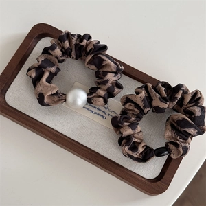 Detailed view of leopard print scrunchies with faux pearl and black bead accents