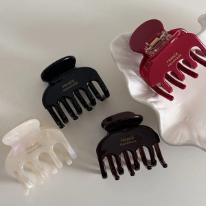 Elegant acetate hair claw clip set with gold lettering on a white shell tray