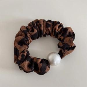 Close-up of leopard print scrunchie with a large pearl detail and textured fabric