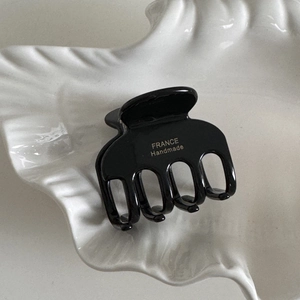 Detail of glossy black acetate hair claw showing the golden France Handmade text logo