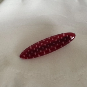 Detail view of oval dark red hair clip with white polka dots and glossy resin finish