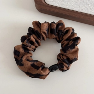 Macro detail of leopard print hair scrunchie with textured fabric and black decor