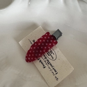 Detail of red strawberry hair clip with white dots on a decorative ceramic tray