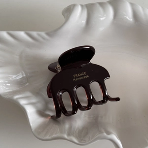 Detailed macro view of deep brown acetate shark hair clip with golden handmade logo