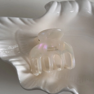Close-up of pearlescent white acetate hair claw clip with gold France Handmade logo